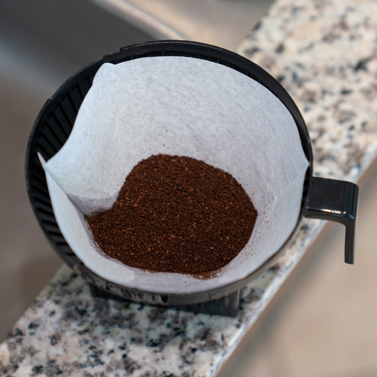 Ground coffee in a No.4 paper filter inside a Moccamaster brew basket