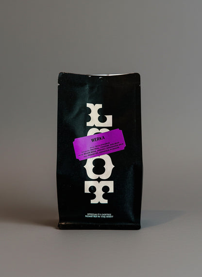 Black coffee bag with a purple label on a white background